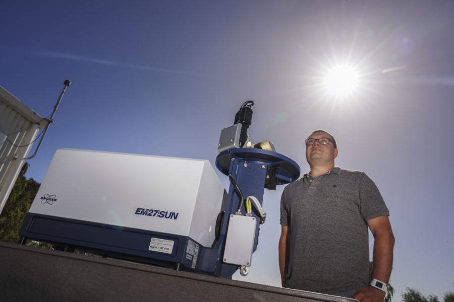 Scientist stands next to Fourier transform spectrometer, which takes measurements of the sun's infrared spectra to work out the amount of several greenhouse gases in the atmosphere.